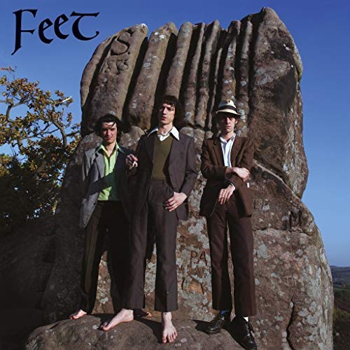 Album cover: three men in suits stand before a large rock formation.