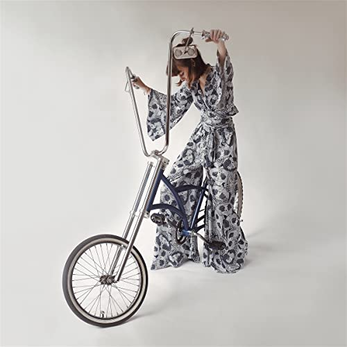 Woman in patterned clothing posing with a vintage blue bicycle.