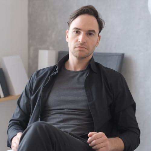 Portrait of a man in a dark shirt, looking at the camera.
