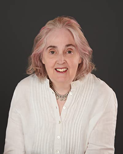 Portrait of a smiling woman with short, wavy pink and grey hair.