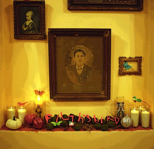 Album cover with framed portraits, candles, and decorative elements.