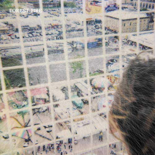 The alt text for the image is: "Grainy album cover with a person's head and cityscape."