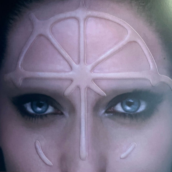 Close-up of eyes beneath a pale, geometric wind rose design.