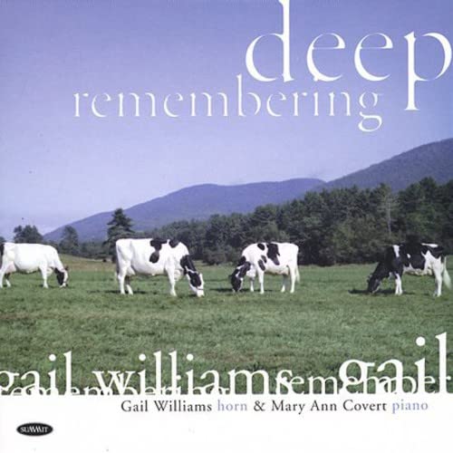 CD cover with cows grazing in a green field and mountains.