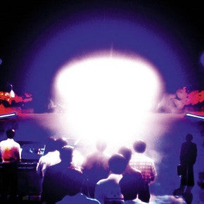 Silhouettes of people facing a bright, glowing light in the dark.