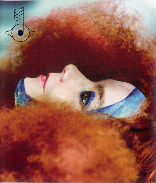 Close-up of a person with vibrant blue eyeshadow and orange fur.
