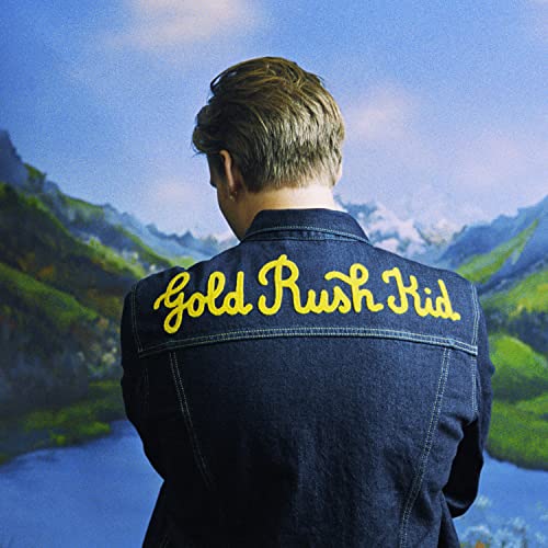 George Ezra seen from behind wearing a denim jacket with Gold Rush Kid embroidered.