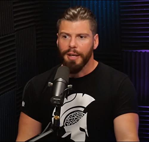 Bearded man speaking into a microphone in a recording studio.