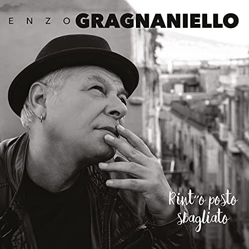 Black and white portrait of Enzo Gragnaniello with a hat, looking upwards.