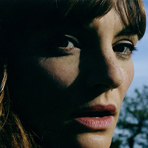 Close-up portrait of a woman with bangs, partially cast in deep shadow.