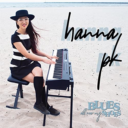 Woman playing keyboard on beach, album cover for Hanna PK’s “Blues All Over My Shoes.”