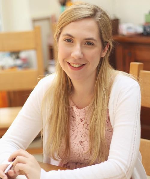 Young woman with blonde hair smiling, holding a pen.