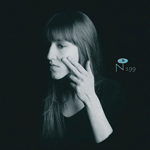 Black and white portrait of a woman touching her cheek against a dark background.