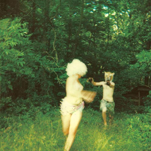 Two figures in animal masks running through a green, overgrown field.