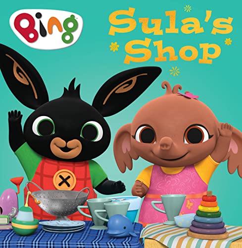 Bing and Sula standing behind a table with toys on a teal background.