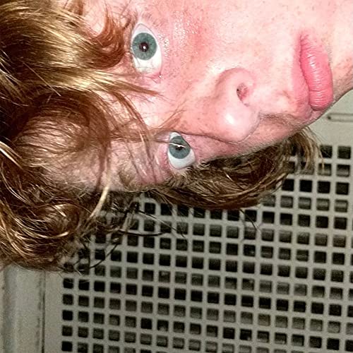Close-up of a person with curly hair, looking upwards with wide eyes.
