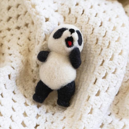 Needle-felted panda charm with a red heart, resting on white yarn.