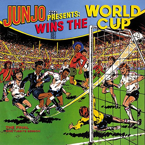 Soccer players in action on a green field with a goal and crowd background.