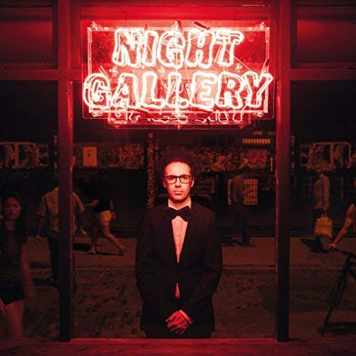 Man in suit poses before a glowing "NIGHT GALLERY" neon sign.