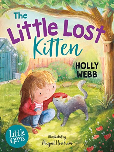 A girl with a yellow hair bow pets a grey kitten in a garden.