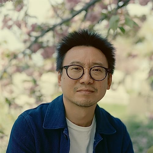 Portrait of a man with glasses, facing forward, with pink blossoms.