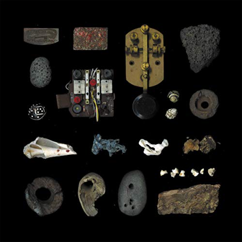 A collection of assorted small objects, stones, and mechanical parts arranged on black background.