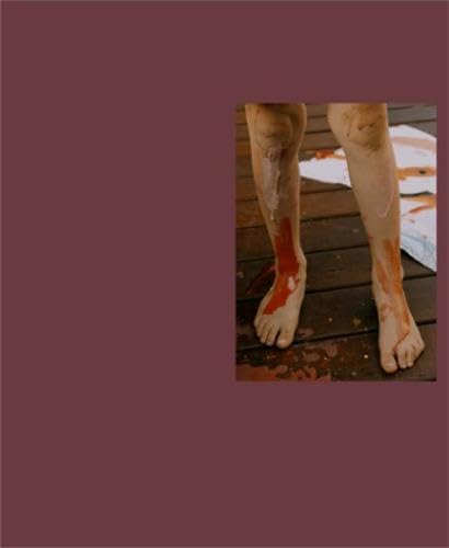 Feet with red paint on a wooden deck, close-up view.