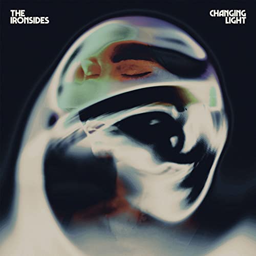 Album cover showing a distorted, reflective metallic face against a dark background.