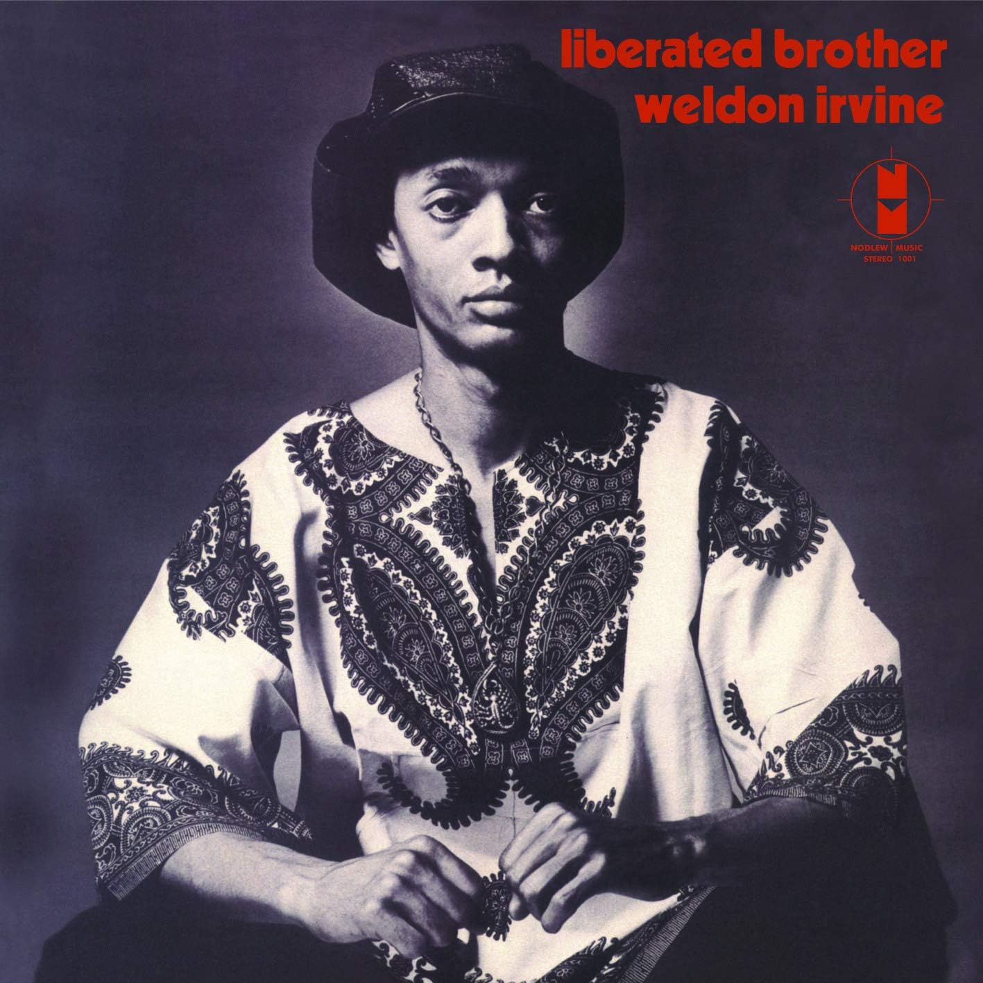 Black and white portrait of Weldon Irvine wearing a patterned dashiki and hat.
