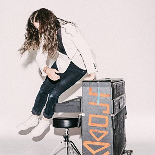 Man with long hair sitting on a speaker, album cover art.