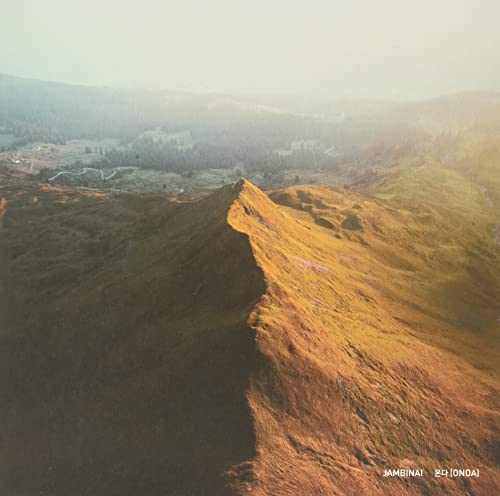 Aerial view of a golden mountain ridge under a hazy sky.