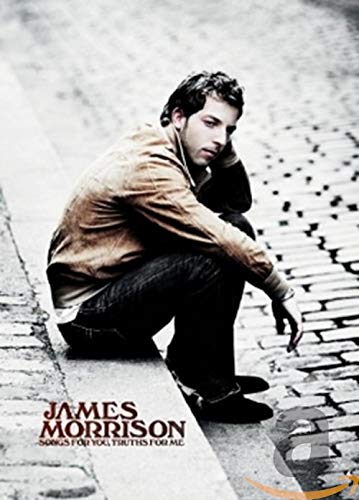 Man crouches on sidewalk curb, looking down with elbow on knee.