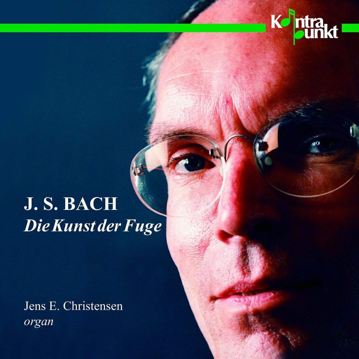Close-up portrait of Jens E. Christensen wearing glasses on a dark blue background.