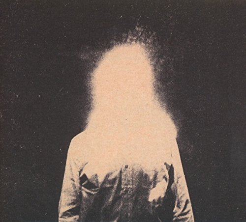 Blurred figure in a jacket against a dark, grainy background.