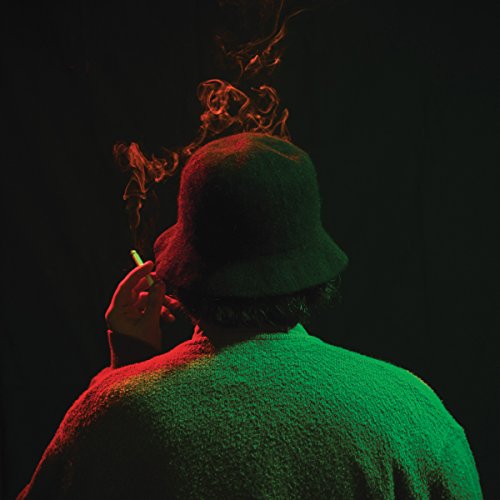 Person with a bucket hat smoking, illuminated by red and green light.