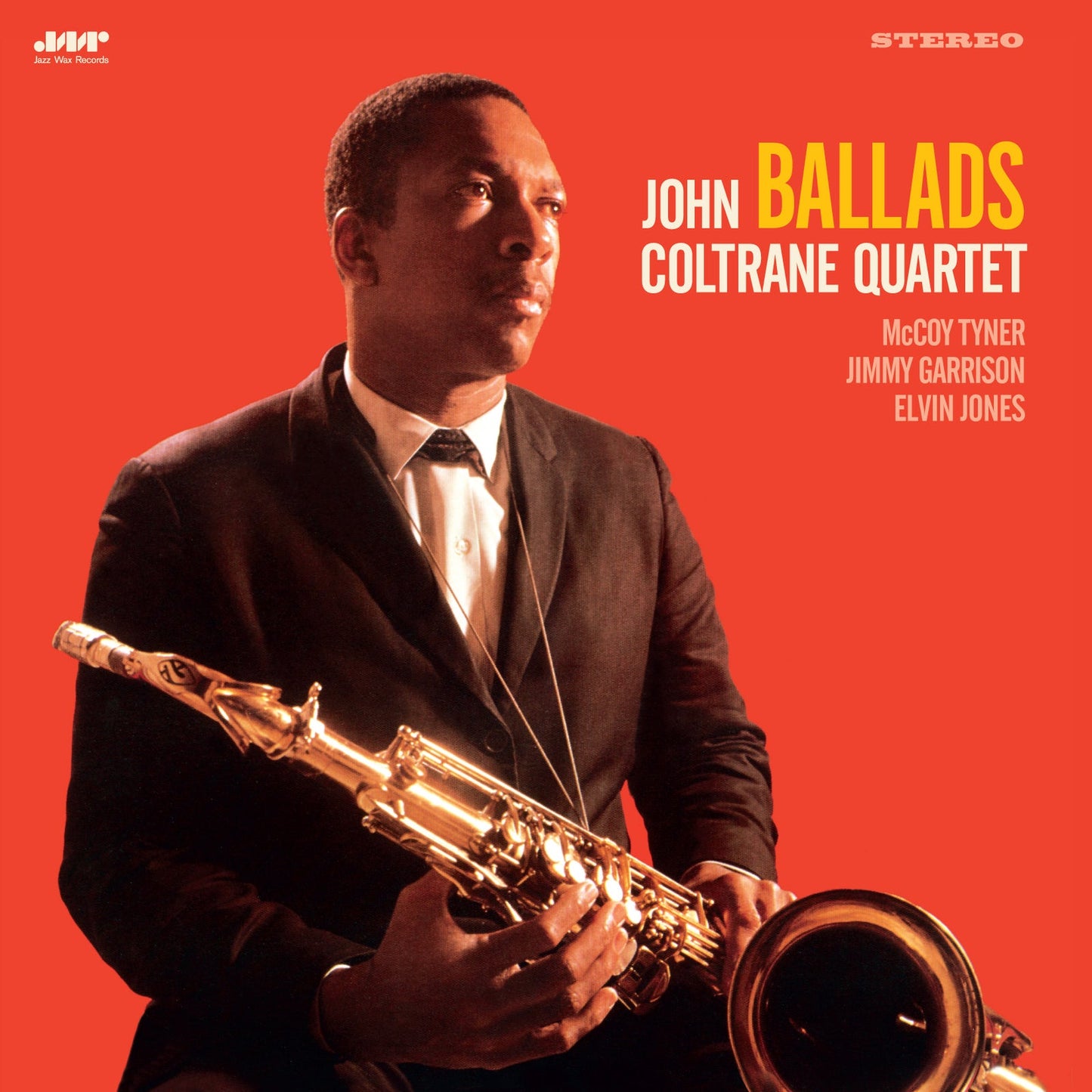 John Coltrane in a suit holding a saxophone against a bright red background.