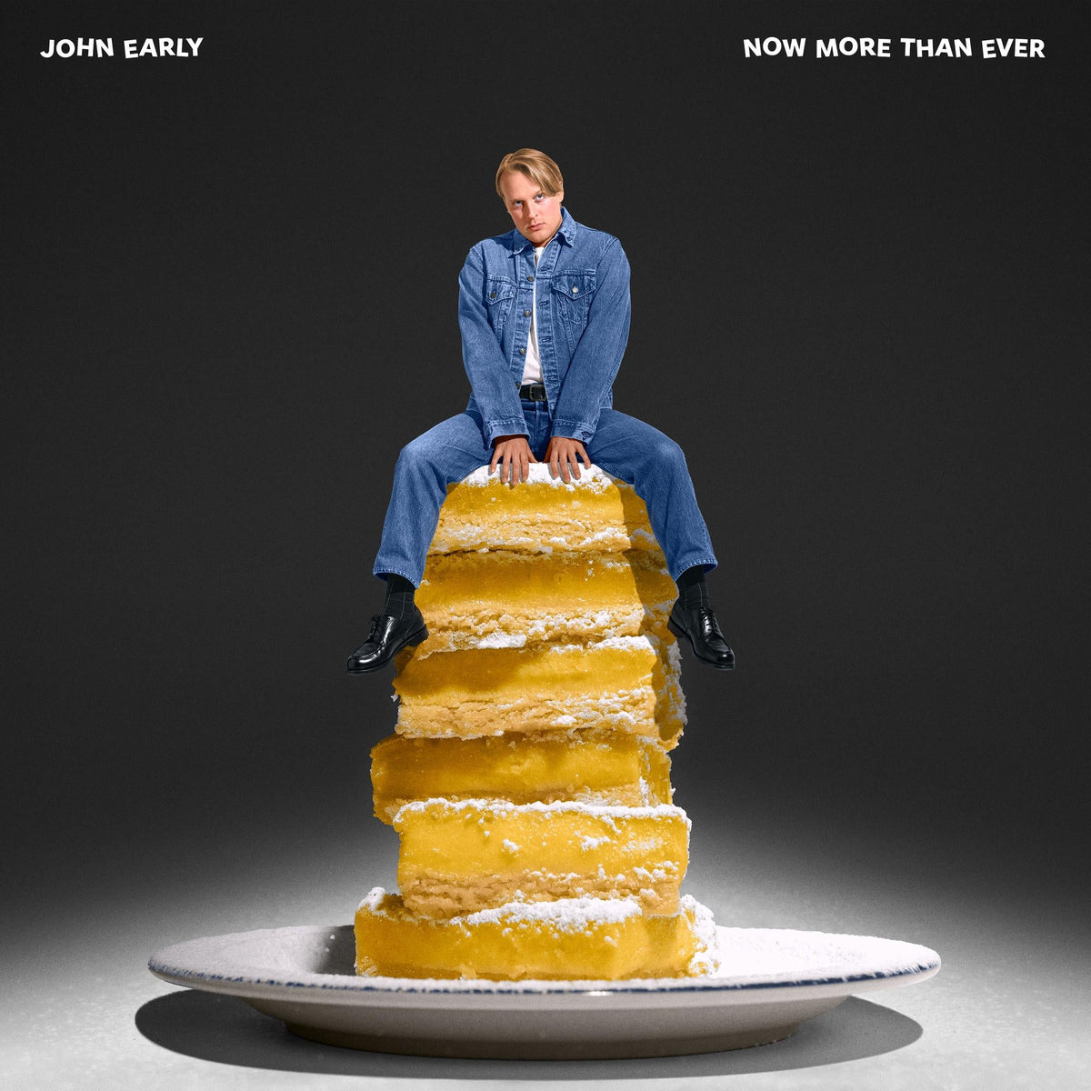 John Early sits atop a tall stack of lemon bars on a white plate.