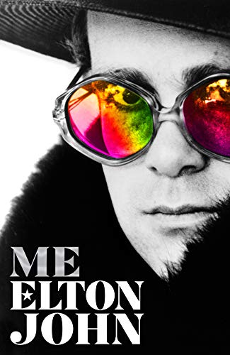 Black and white portrait of Elton John wearing colorful glasses and a dark hat.