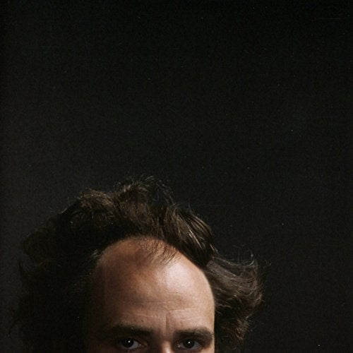 Close-up portrait of a man with receding hairline and intense gaze.