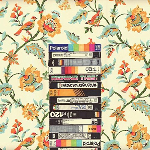 Stack of VHS tapes and a Polaroid camera against a floral background.