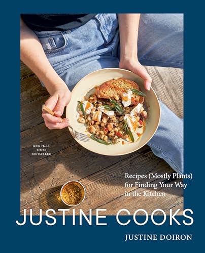 A person in jeans holds a plate of food over a wooden deck.