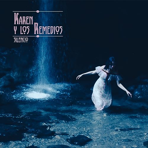 A woman in a white dress stands in a dark stream near a waterfall.