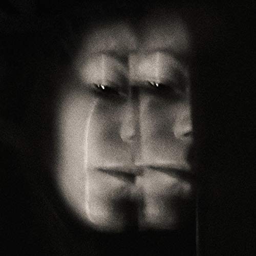 Blurred, grayscale portrait of a person with shadowed eyes.