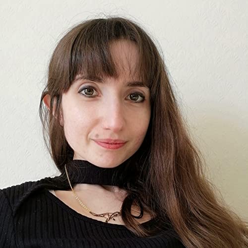 Woman with long brown hair and bangs wearing a black top and gold necklace.
