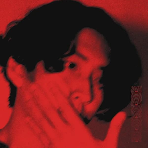 Red-toned album cover featuring a distorted close-up of a person’s face.