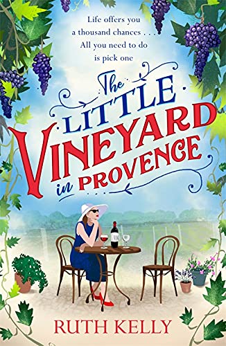 A woman in a blue dress sits at a cafe table in a vineyard.