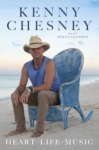 Kenny Chesney sits in a blue rocking chair on a beach.