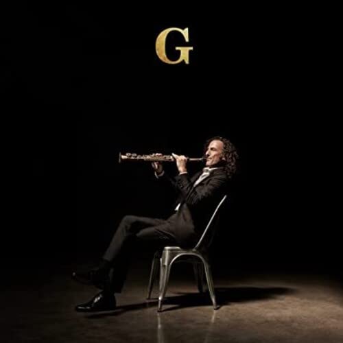Kenny G playing saxophone, seated in a chair against a black background.