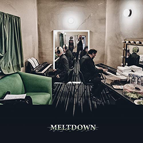 Musicians in a dressing room reflected in a large mirror with the word MELTDOWN below.