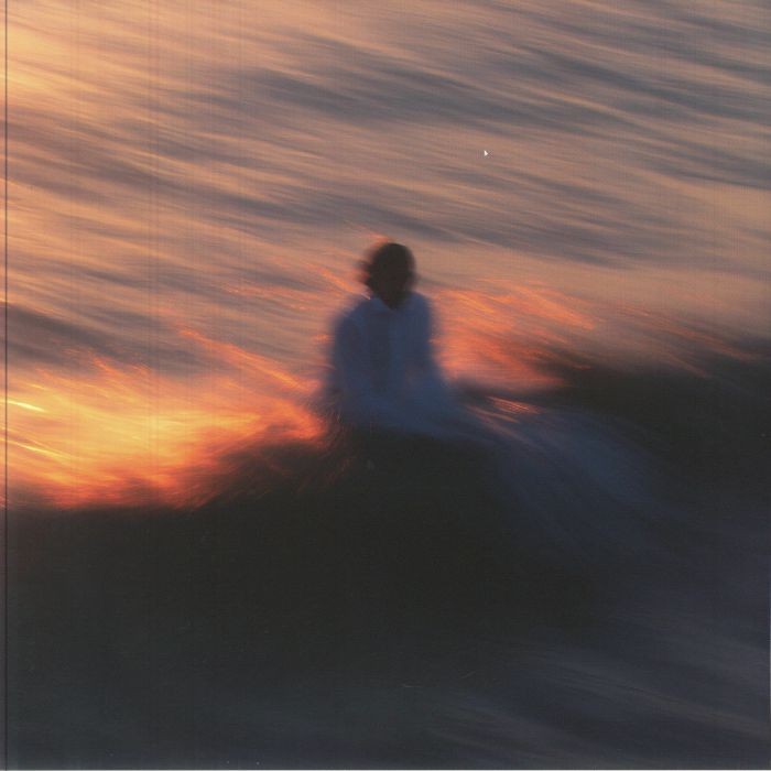 A blurry silhouette of a person standing in water at sunset.